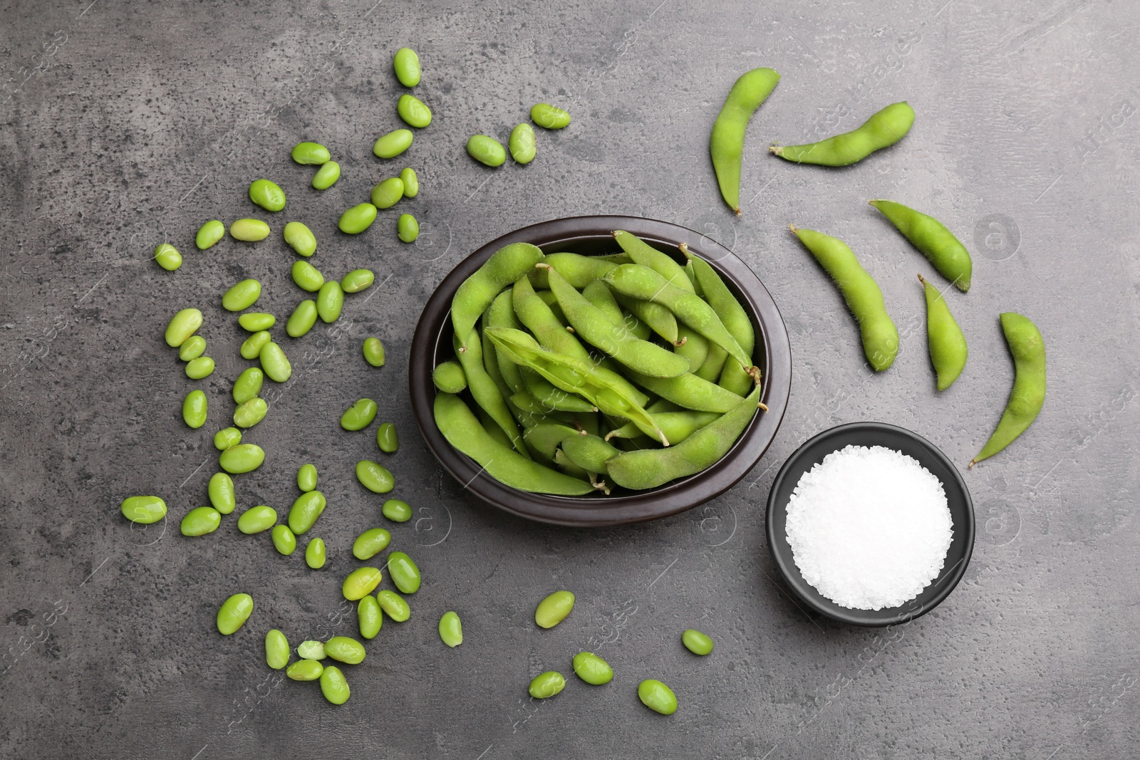 Photo of Raw green edamame soybeans and pods on grey table, flat lay