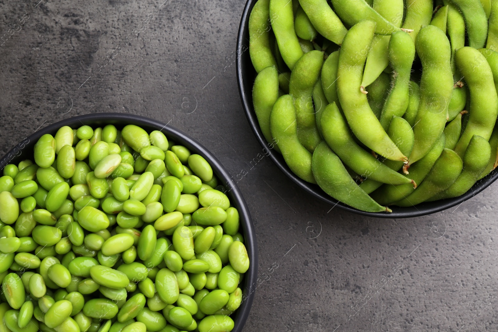 Photo of Raw green edamame soybeans and pods on grey table, top view