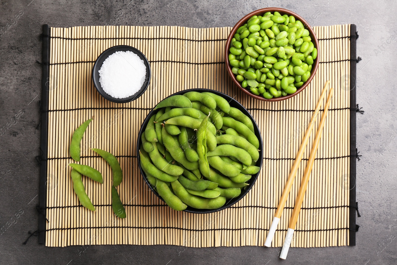 Photo of Raw green edamame soybeans and pods on grey table, top view