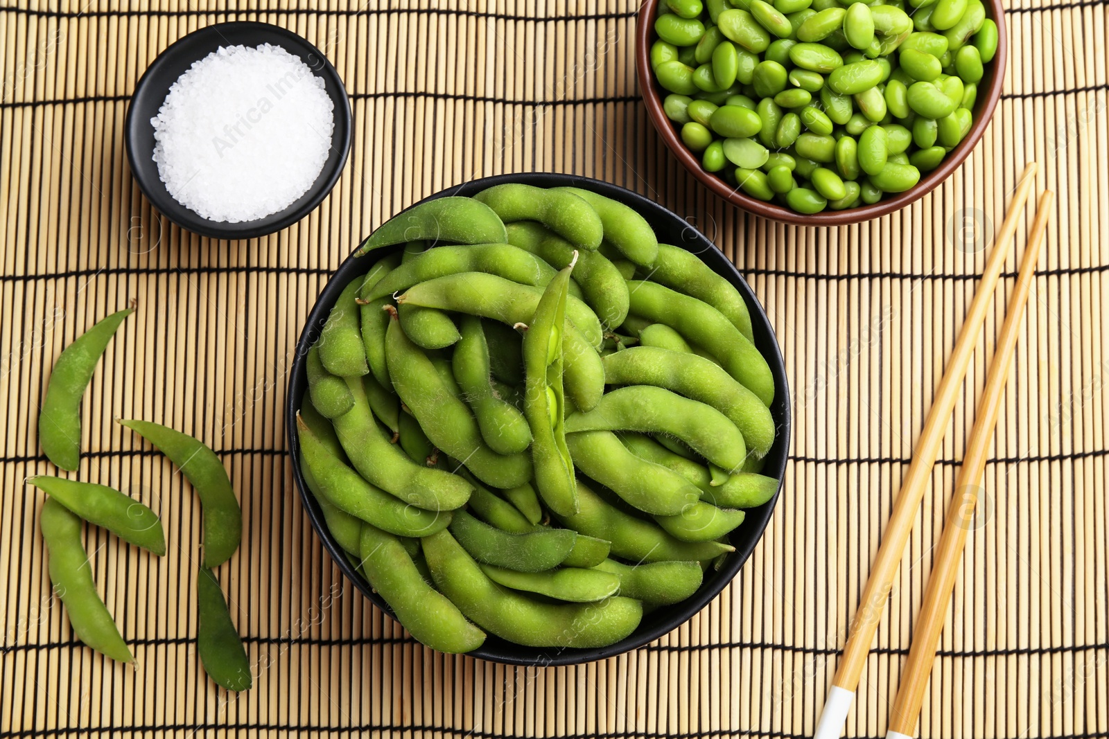 Photo of Raw green edamame soybeans and pods on wicker mat, flat lay