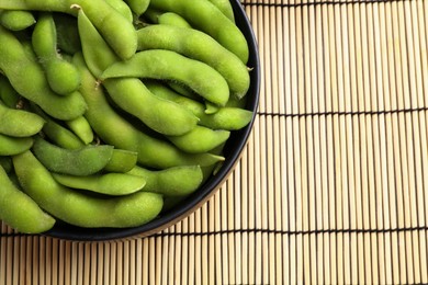 Photo of Raw green edamame pods on wicker mat, top view. Space for text