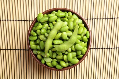 Photo of Raw green edamame soybeans and pods on wicker mat, top view