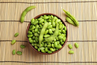 Photo of Raw green edamame soybeans and pods on wicker mat, flat lay