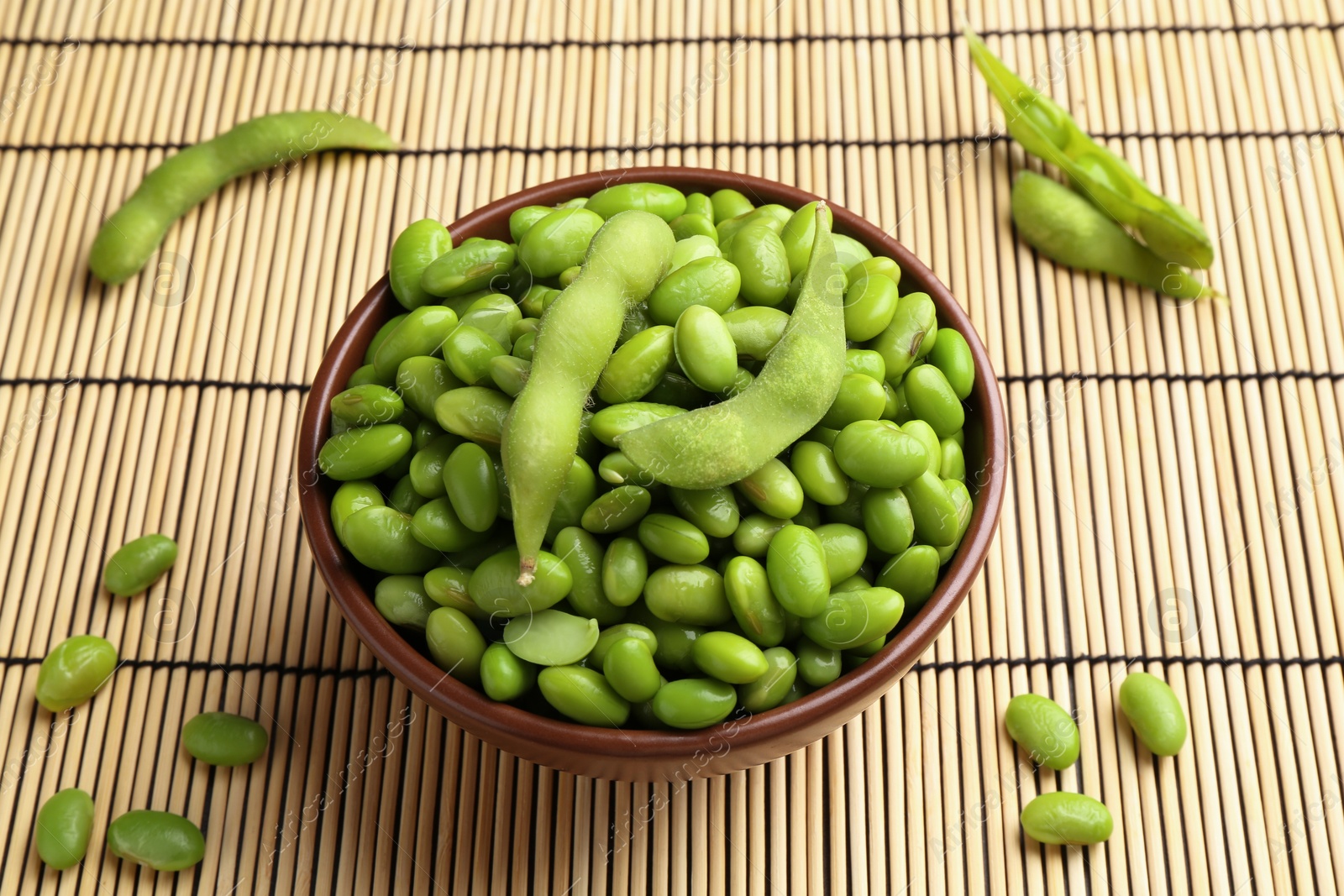 Photo of Raw green edamame soybeans and pods on wicker mat