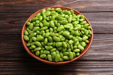 Photo of Raw green edamame soybeans in bowl on wooden table