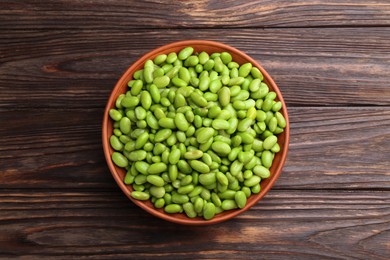 Photo of Raw green edamame soybeans in bowl on wooden table, top view