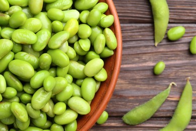 Photo of Raw green edamame soybeans and pods on wooden table, top view