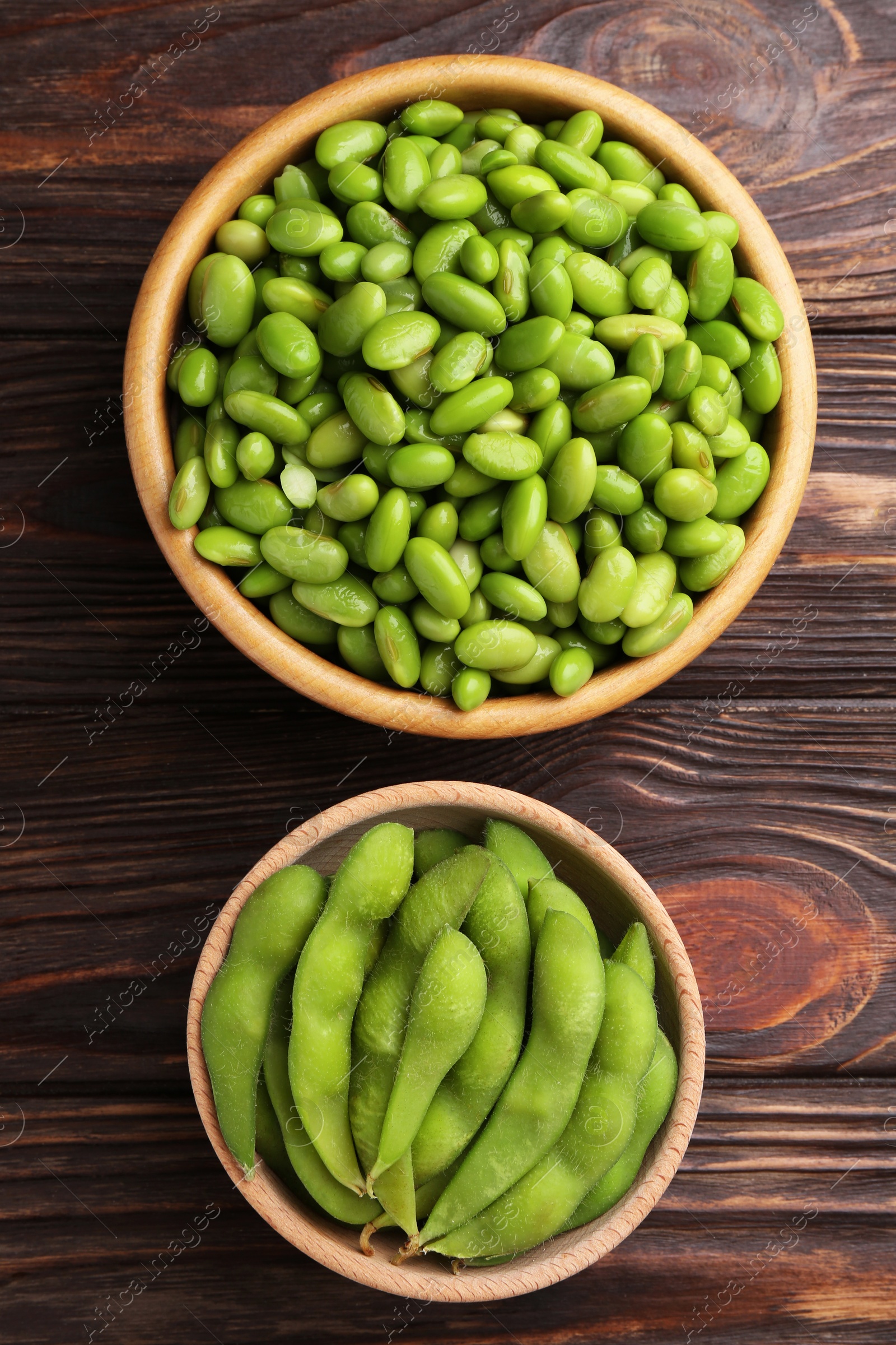 Photo of Raw green edamame soybeans and pods on wooden table, top view