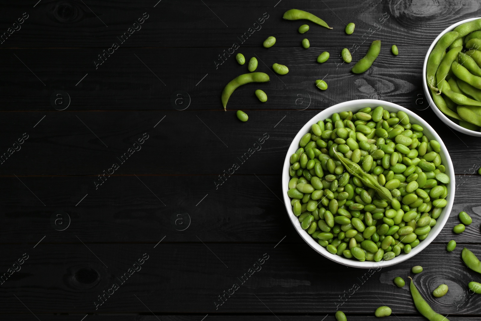 Photo of Raw green edamame soybeans and pods on wooden table, flat lay. Space for text