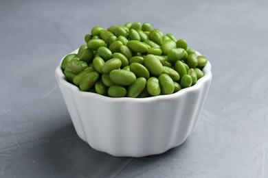 Fresh edamame soybeans in bowl on grey textured table, closeup