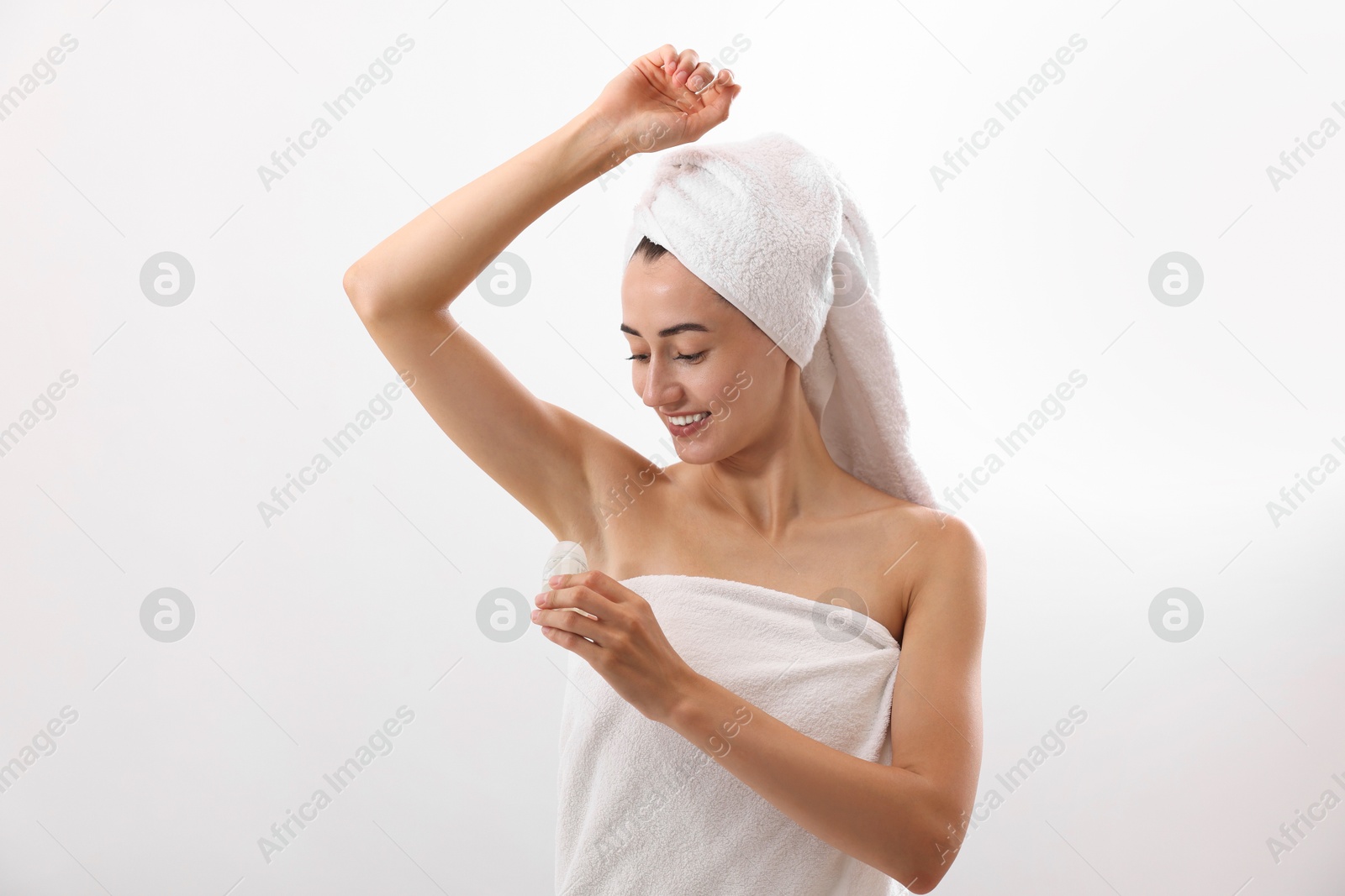 Photo of Smiling woman applying roll-on deodorant on white background