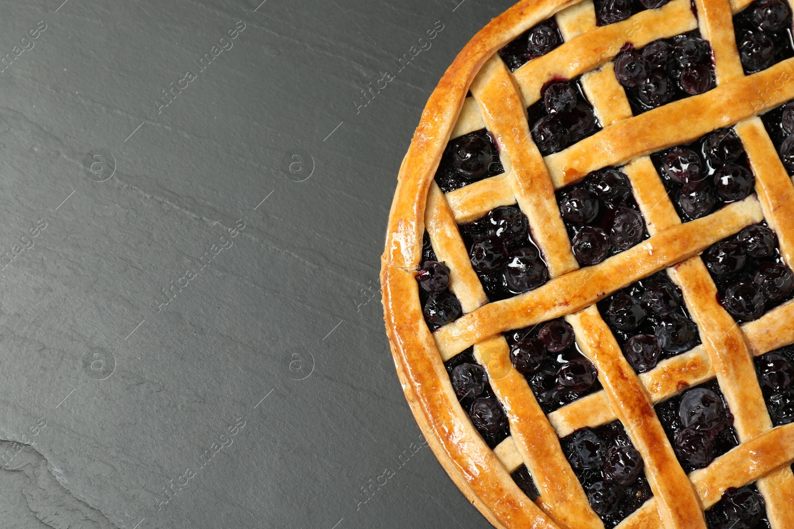 Photo of Tasty homemade pie with blueberries on grey textured table, top view. Space for text