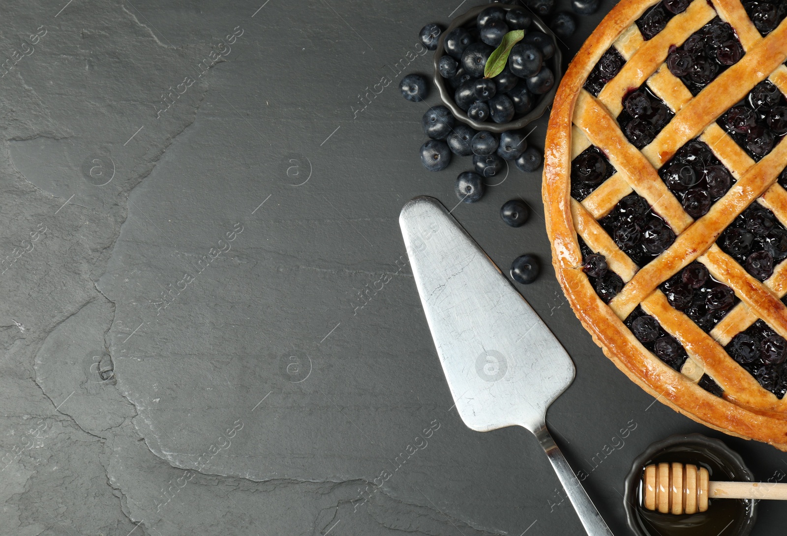 Photo of Tasty homemade pie with blueberries served on grey textured table, flat lay. Space for text