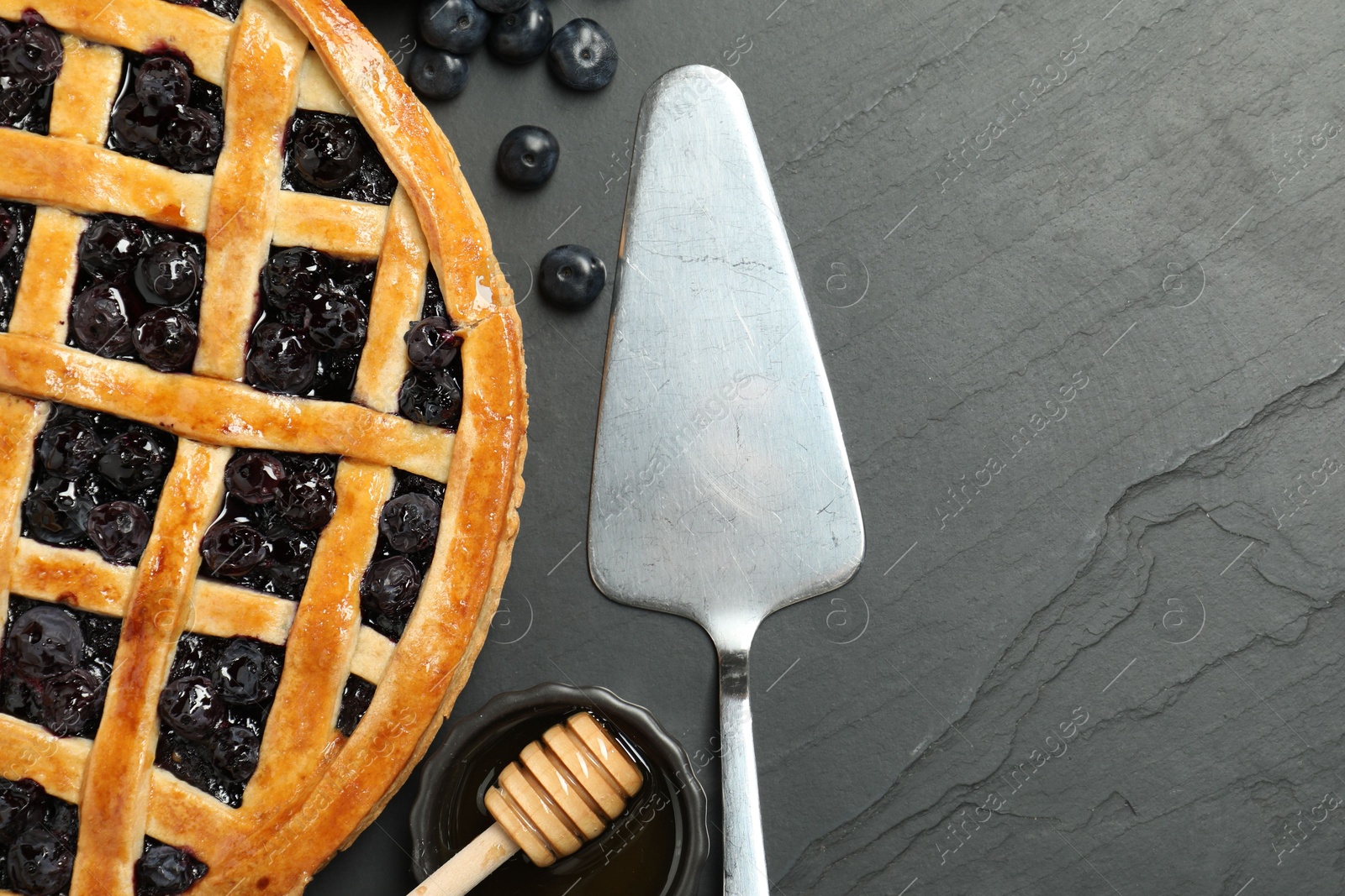 Photo of Tasty homemade pie with blueberries served on grey textured table, flat lay. Space for text