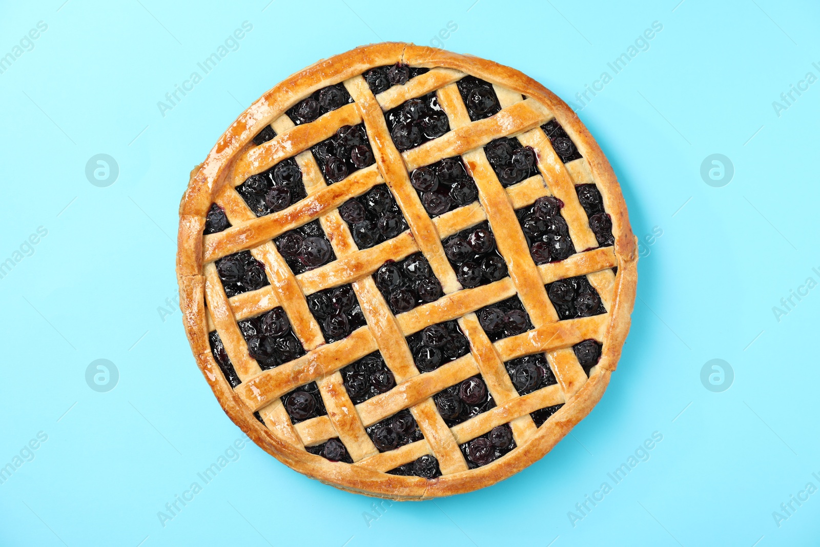 Photo of Tasty homemade pie with blueberries on light blue table, top view