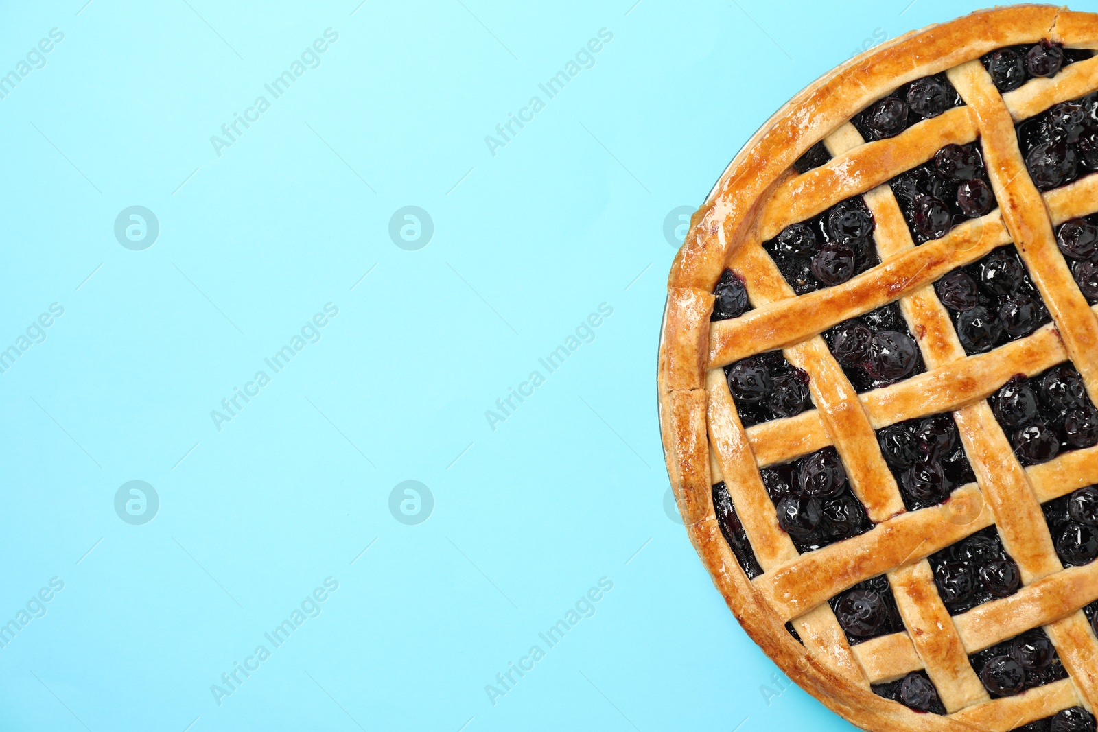 Photo of Tasty homemade pie with blueberries on light blue table, top view. Space for text