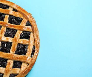 Photo of Tasty homemade pie with blueberries on light blue table. Space for text