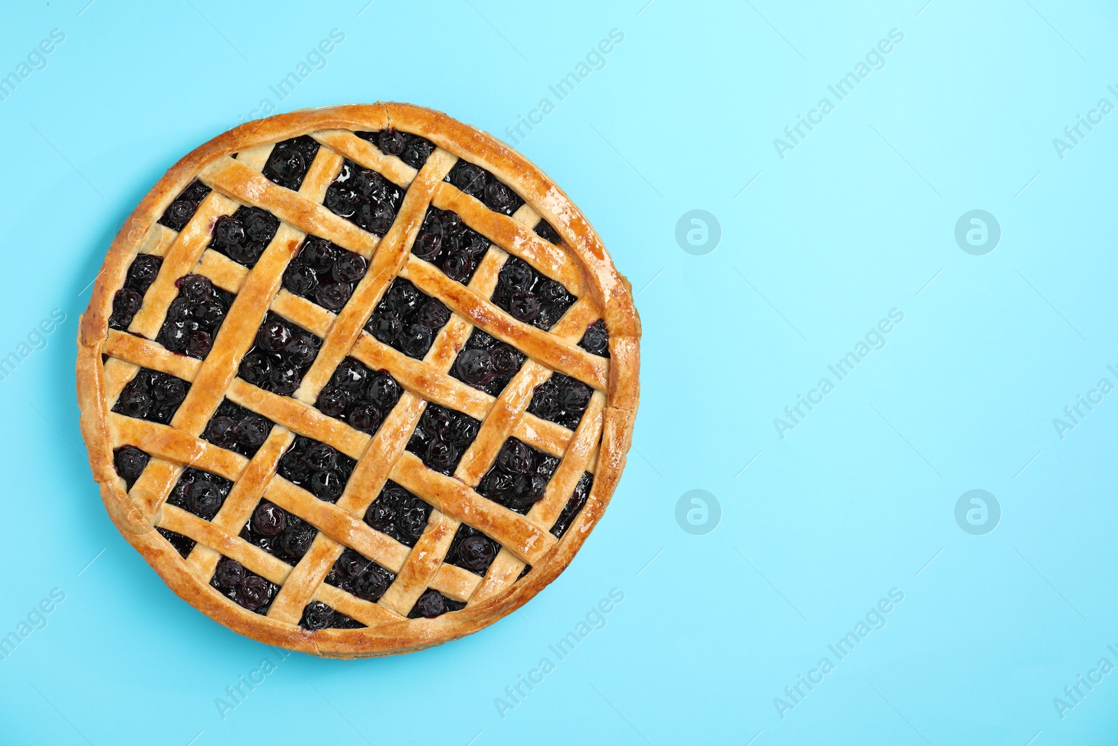 Photo of Tasty homemade pie with blueberries on light blue table, top view. Space for text