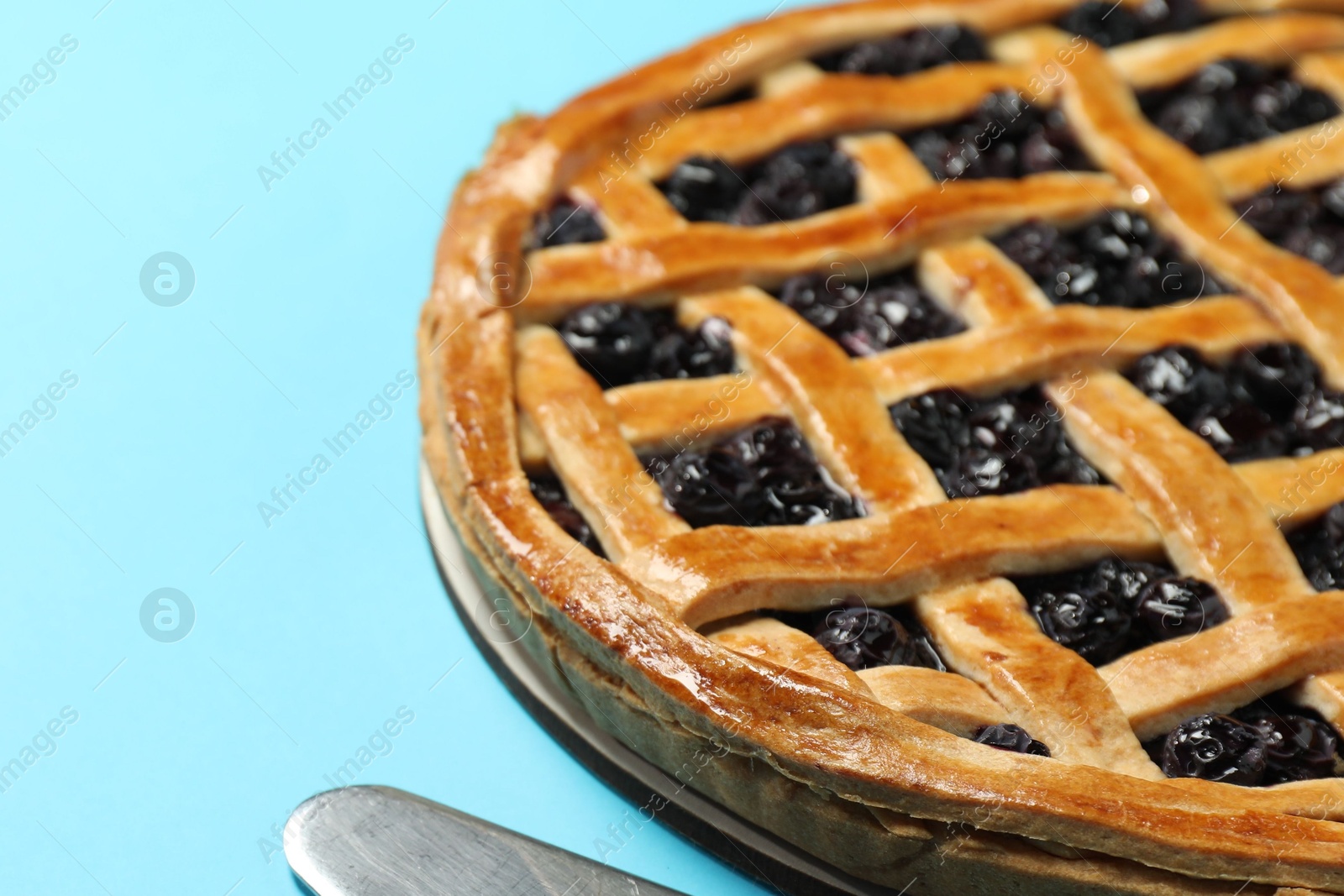 Photo of Tasty homemade pie with blueberries on light blue table, closeup