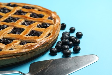 Photo of Tasty homemade pie with blueberries and server on light blue table, closeup