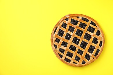 Photo of Tasty homemade pie with blueberries on yellow table, top view. Space for text