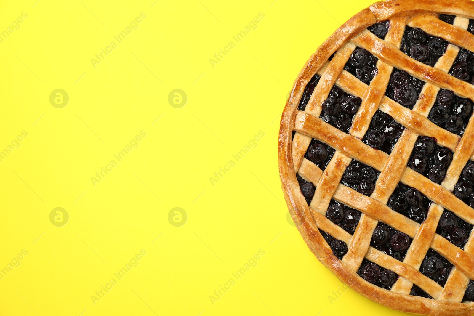 Photo of Tasty homemade pie with blueberries on yellow table, top view. Space for text