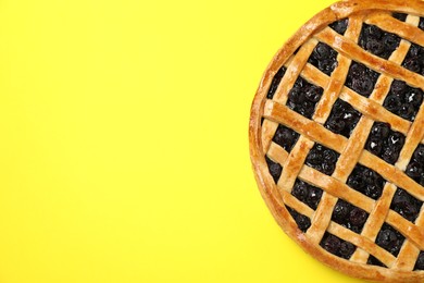 Photo of Tasty homemade pie with blueberries on yellow table, top view. Space for text