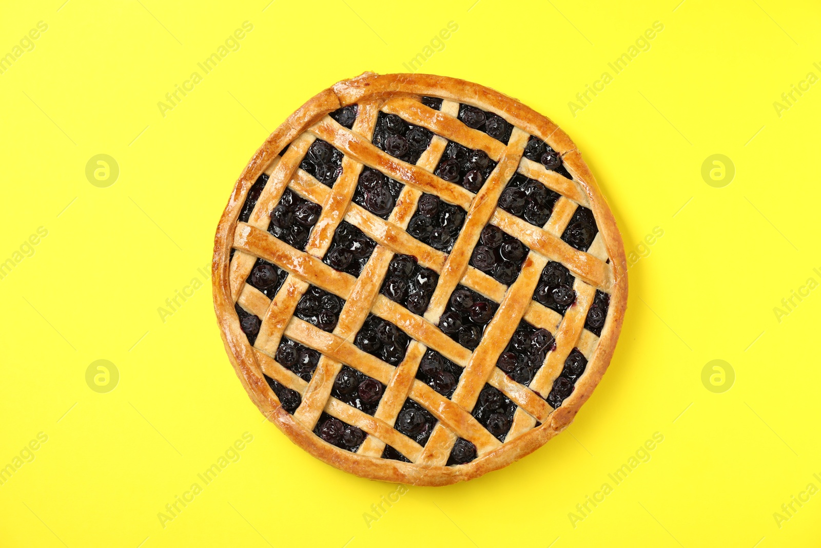 Photo of Tasty homemade pie with blueberries on yellow table, top view