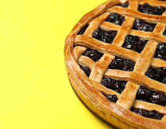 Photo of Tasty homemade pie with blueberries on yellow table, closeup. Space for text