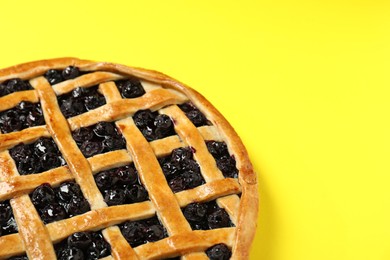 Photo of Tasty homemade pie with blueberries on yellow table, closeup. Space for text