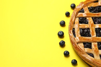 Photo of Tasty homemade pie with blueberries on yellow table, closeup. Space for text