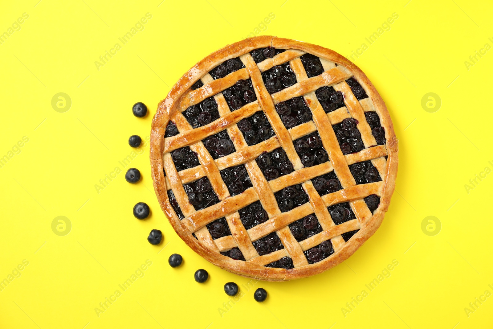 Photo of Tasty homemade pie with blueberries on yellow table, top view