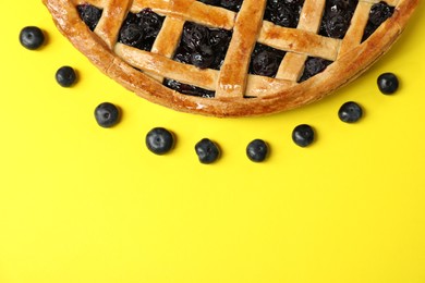 Photo of Tasty homemade pie with blueberries on yellow table, top view. Space for text