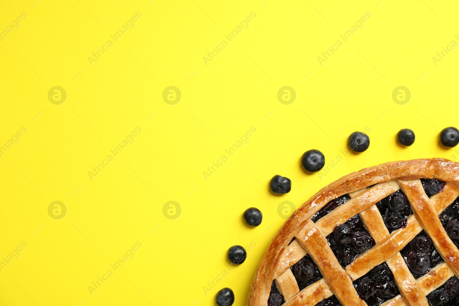 Photo of Tasty homemade pie with blueberries on yellow table, top view. Space for text