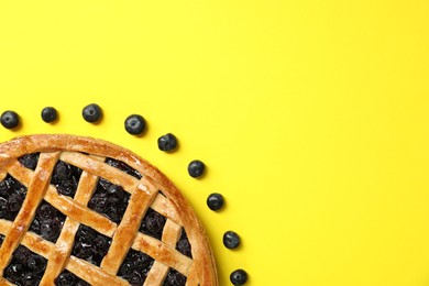 Photo of Tasty homemade pie with blueberries on yellow table, top view. Space for text