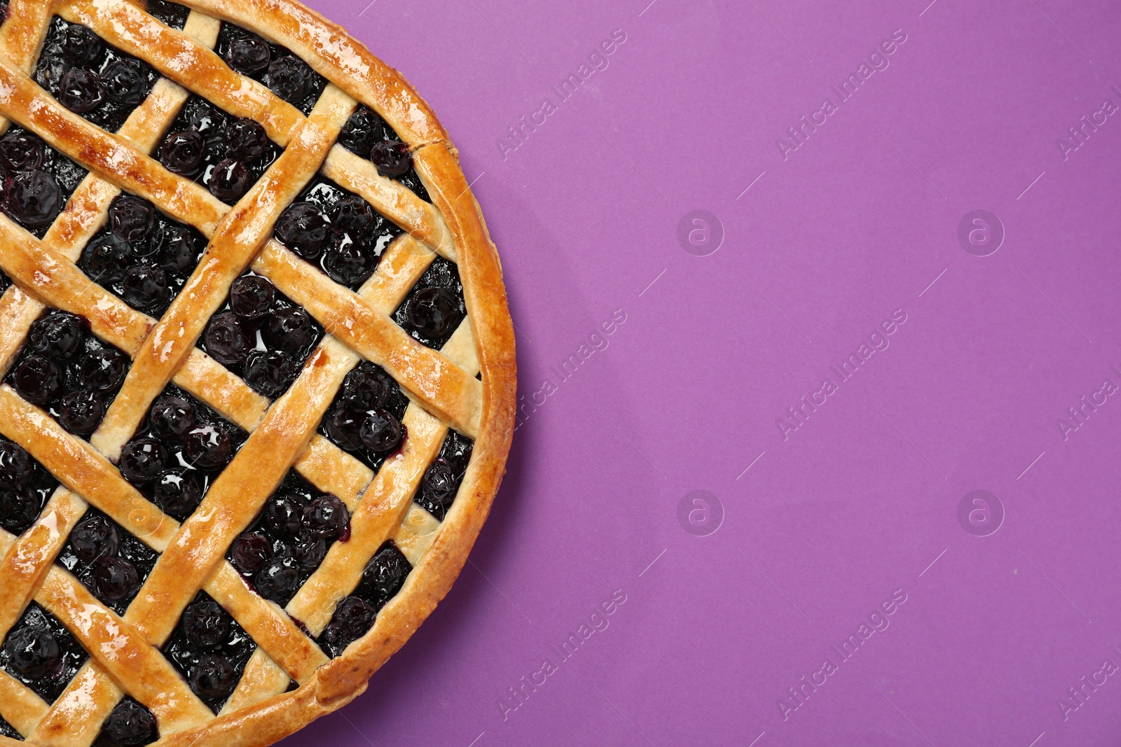 Photo of Tasty homemade pie with blueberries on purple table, top view. Space for text