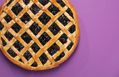 Photo of Tasty homemade pie with blueberries on purple table, top view. Space for text