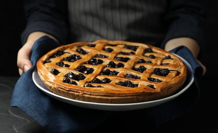 Photo of Woman holding tasty homemade pie with blueberries over table, closeup