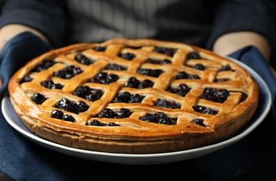 Photo of Woman holding tasty homemade pie with blueberries, closeup