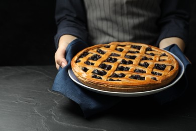 Photo of Woman holding tasty homemade pie with blueberries over grey textured table, closeup