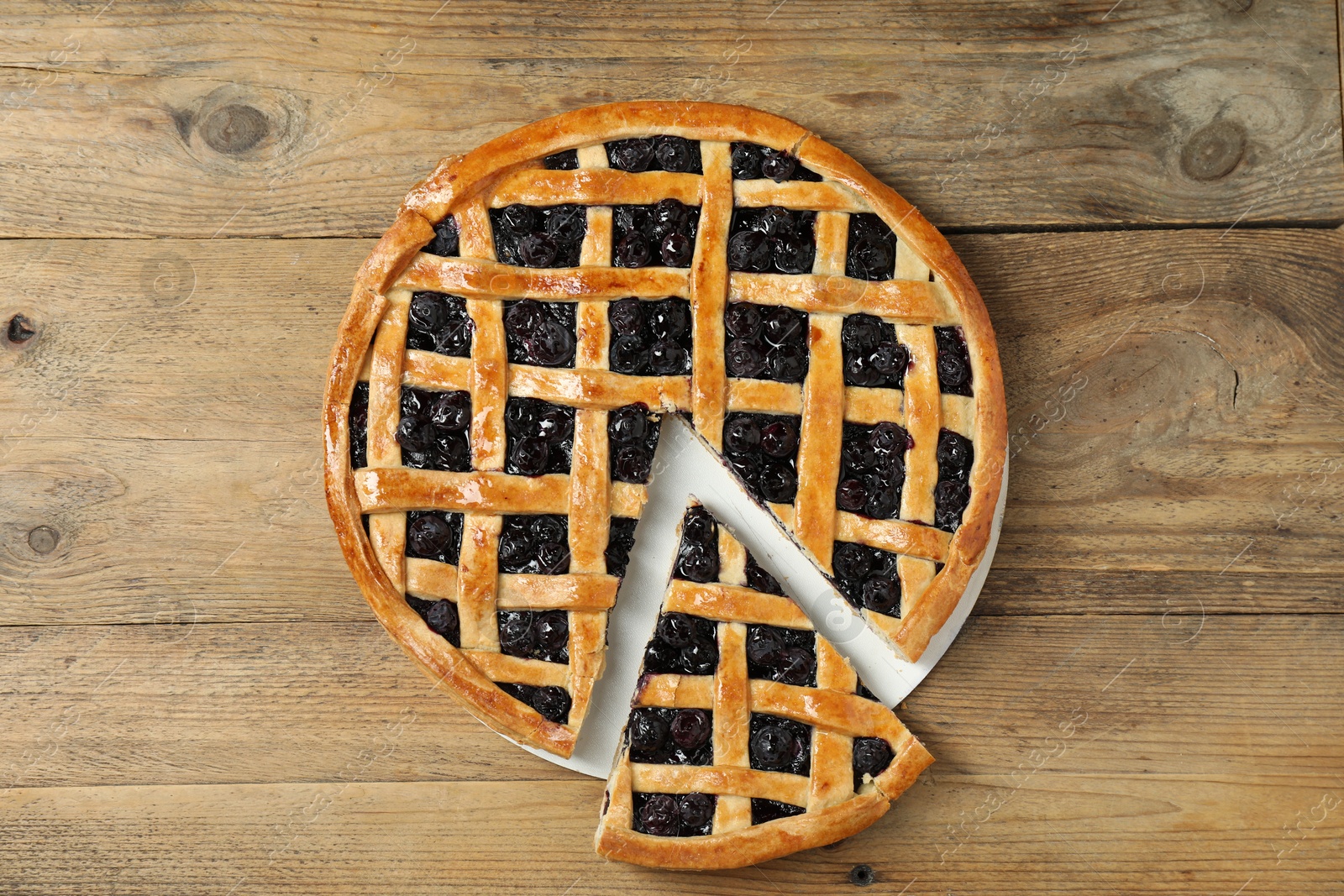 Photo of Tasty homemade pie with blueberries on wooden table, top view