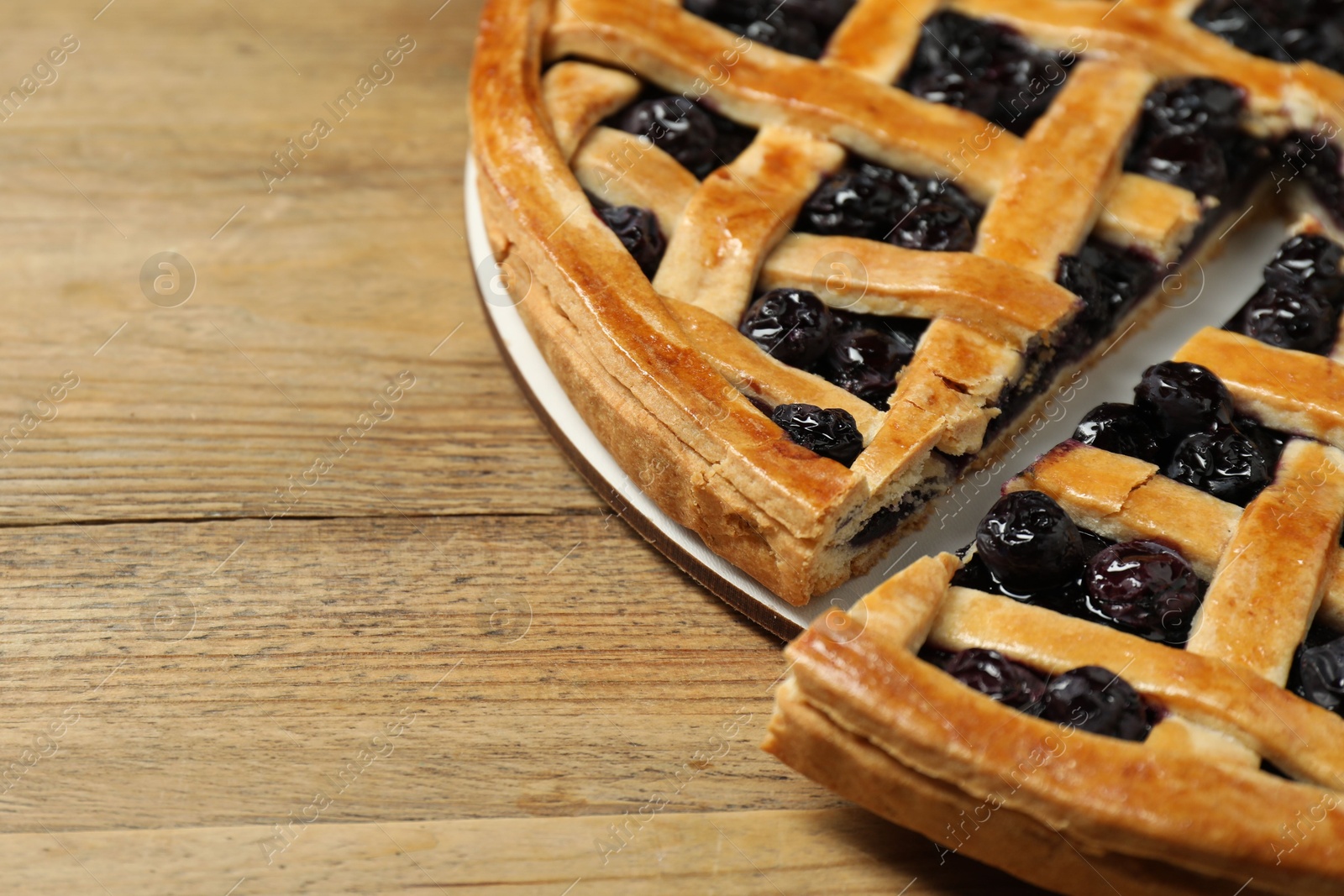 Photo of Tasty homemade pie with blueberries on wooden table, closeup. Space for text