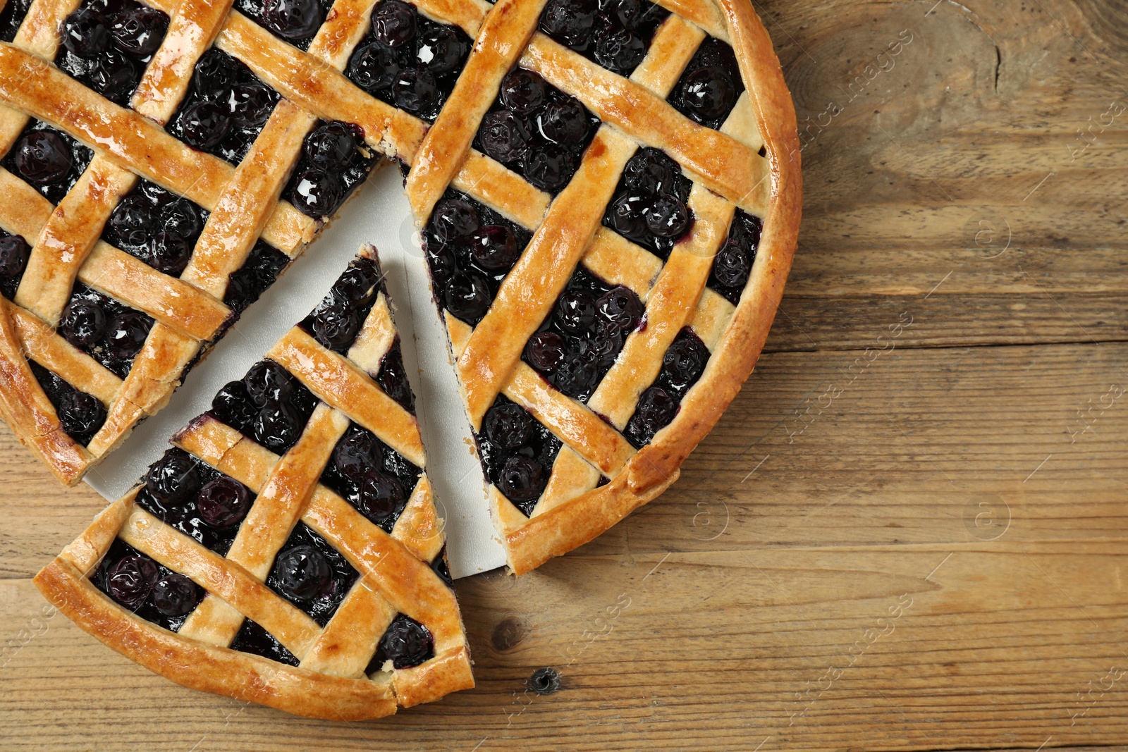 Photo of Tasty homemade pie with blueberries on wooden table, top view. Space for text