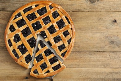 Photo of Taking piece of delicious homemade blueberry pie with server on wooden table, top view. Space for text