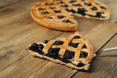 Piece of tasty homemade blueberry pie and server on wooden table, closeup