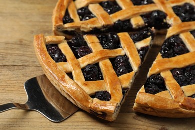 Photo of Taking piece of delicious homemade blueberry pie with server on wooden table, closeup