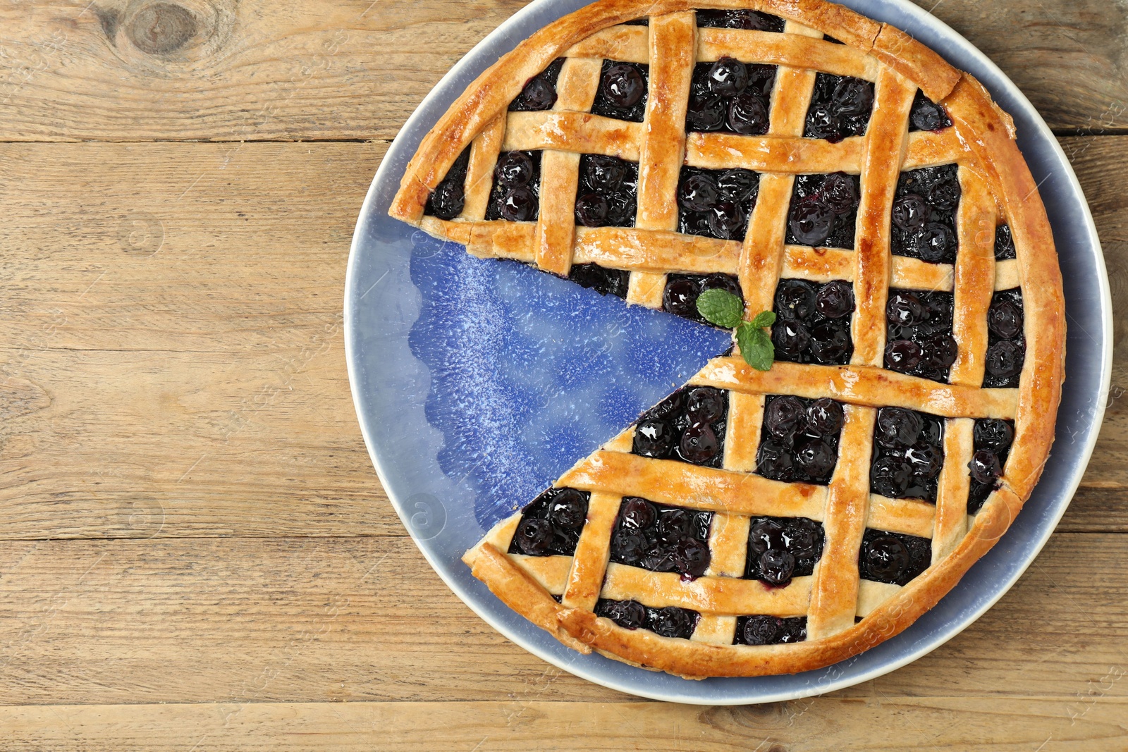 Photo of Tasty homemade pie with blueberries on wooden table, top view