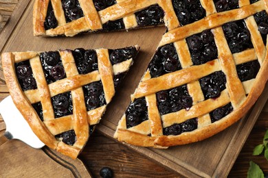 Photo of Tasty homemade pie with blueberries served on wooden table, flat lay