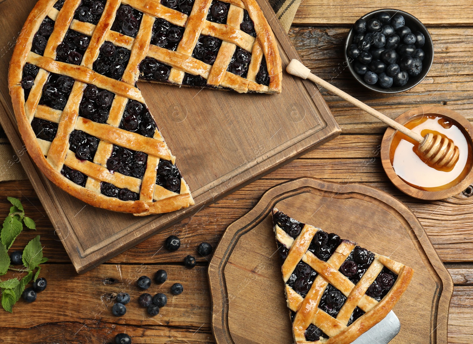 Photo of Tasty homemade pie with blueberries served on wooden table, flat lay