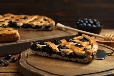 Photo of Piece of tasty homemade pie with blueberries served on wooden table, closeup